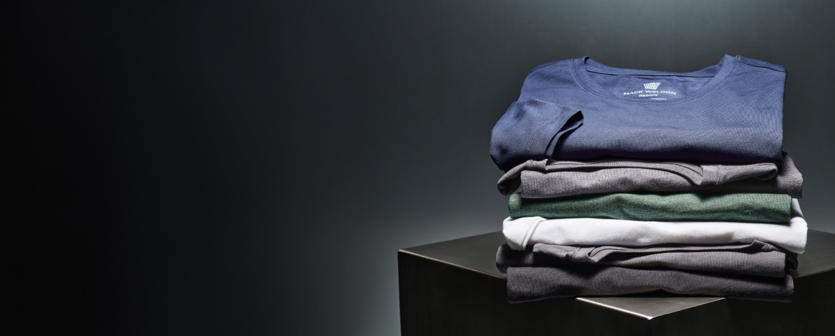 image of a stack of SILVER shirts folded on top of a metal cube